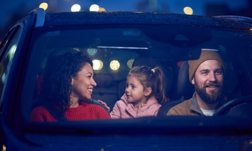 happy family riding together in SUV at night with clear windshield, bright headlights reflecting on wet road, parents and child smiling after service visit, Athens Ford Service Center customers enjoying safe evening drive in Athens GA, improved visibility from new wiper blades and restored headlights, relaxed confident Ford driver during deer season, family friendly dealership experience in Clarke County, night commute with sharp lane markings and no glare, Quick Lane convenience for busy Athens commuters, safe holiday travel after visibility inspection