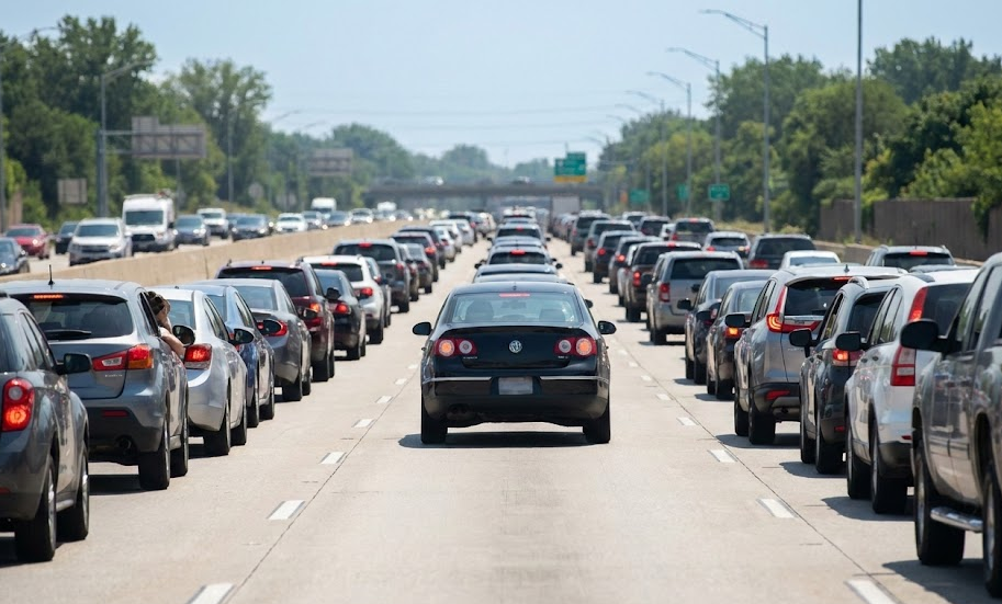 Heavy Atlanta highway traffic on hot summer day, Volkswagen sedan idling in middle lane, long I-285 style backup increasing engine bay heat, Southern driving conditions wearing out car batteries, VW electrical system working hard in congestion, Stone Mountain Volkswagen service for commuters, Atlanta GA stop and go traffic stressing alternator and battery, summer road conditions for Snellville and Stone Mountain VW drivers, VW battery maintenance awareness
