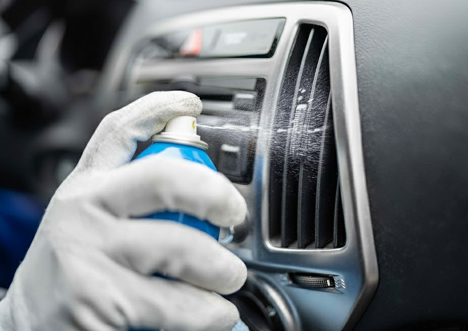 technician spraying cleaner into car AC vent, Audi interior HVAC disinfecting service, removing mold and mildew smell from parked Audi in Naples Florida, high humidity cabin air quality treatment, Audi Naples Service Center HVAC cleaning and cabin air filter replacement, eliminate musty odor in Audi Q5 Q7 A6, protect passengers from allergens, Southwest Florida seasonal resident Audi interior detail