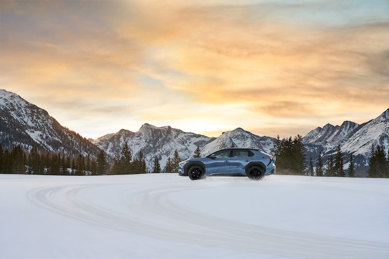 Subaru Solterra electric SUV driving through snowy mountains at sunset. Find the Subaru Solterra at AutoFair Subaru of Haverhill, MA – your destination for adventure-ready electric vehicles.