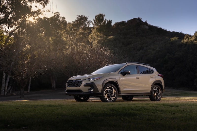 2024 Subaru Solterra electric SUV parked on a gravel road surrounded by trees. Discover the all-electric Subaru Solterra at AutoFair Subaru of Haverhill, MA – perfect for eco-friendly driving in New England.