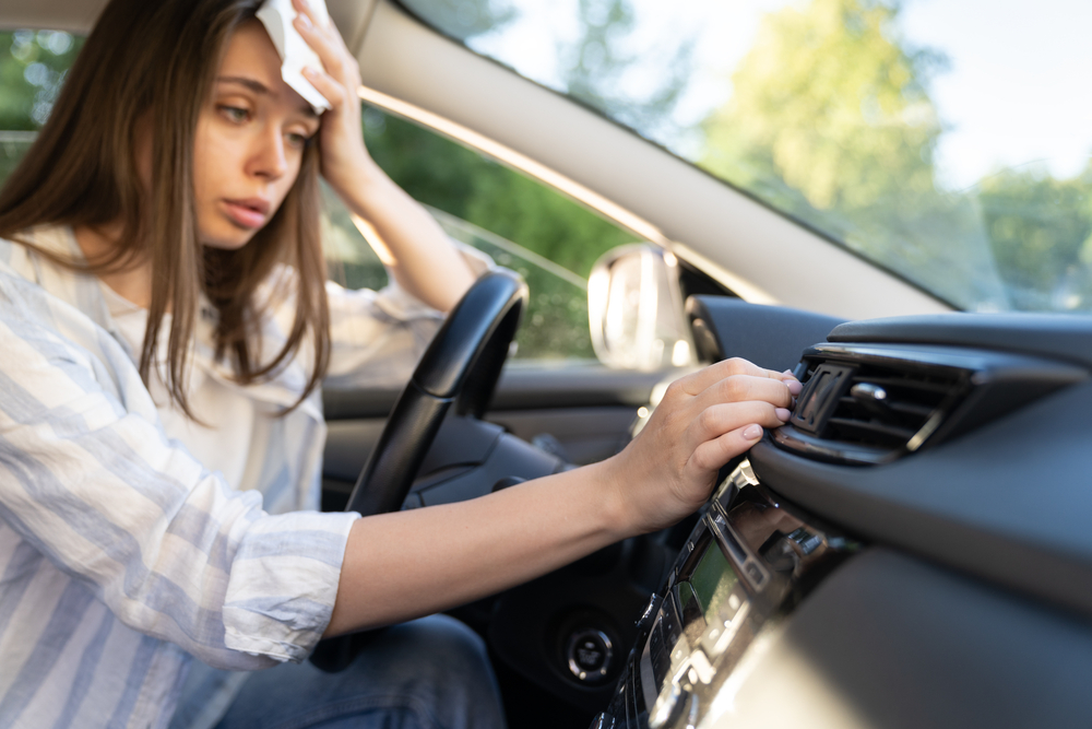 driver sweating in Volkswagen, broken AC in VW car Snellville GA, Volkswagen air conditioning failure Atlanta, car interior heat issue VW, summer AC problems Stone Mountain VW, woman adjusting hot air vent, need AC recharge Volkswagen