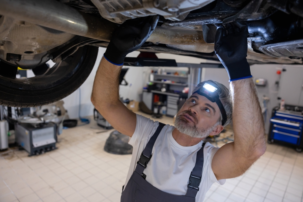 Mechanic inspecting car undercarriage for water damage, Franklin TN collision repair, Cool Springs auto flood diagnostic, vehicle electrical and structural inspection Tennessee summer storm