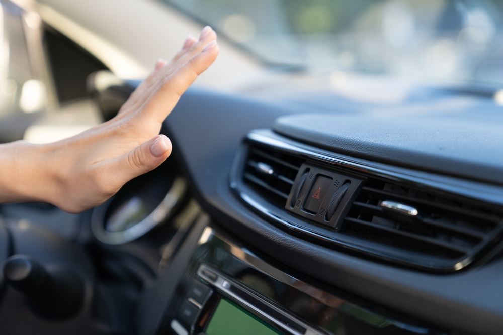 Mazda driver testing car A/C airflow, checking cold air from dashboard vent, Mazda A/C service Florida, hot car interior Florida, driver cooling off in Mazda, Daytona Beach Mazda climate control check, Mazda summer air conditioning inspection