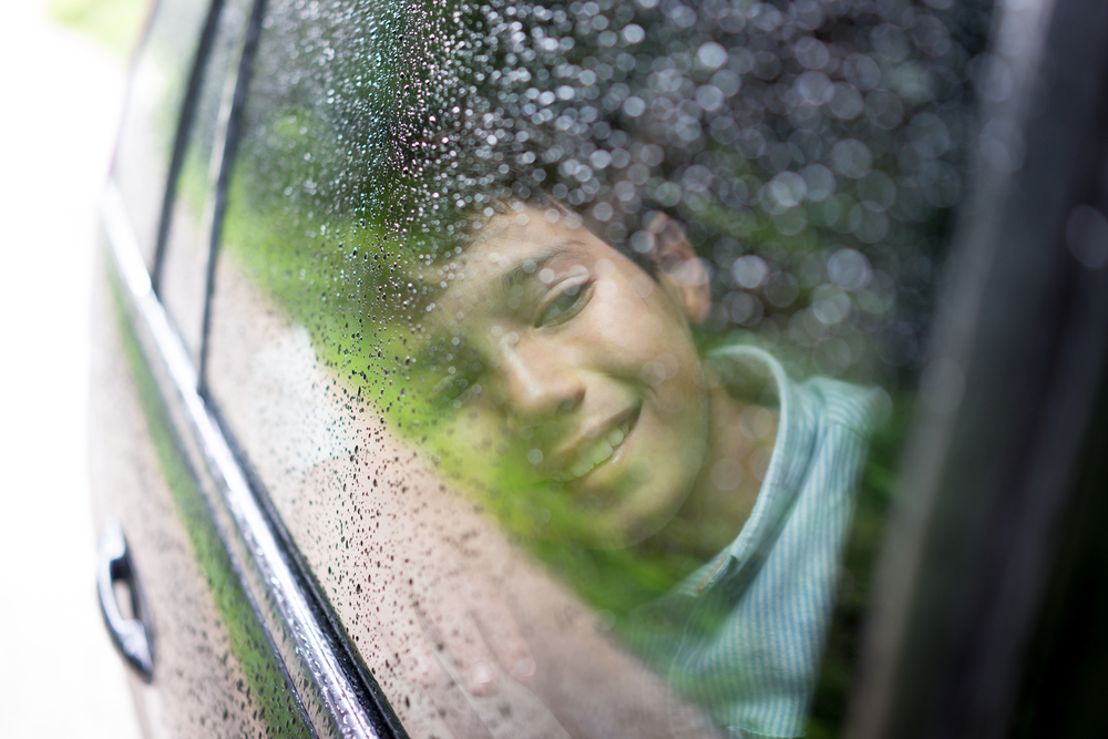Child inside car with rain on window, family safety in Florida storms, Mazda i-ACTIV AWD confidence, Daytona Mazda Service near me, AWD inspection for Daytona Beach drivers, preventive maintenance before rainy season, traction control, stability and braking on wet roads, schedule AWD service online