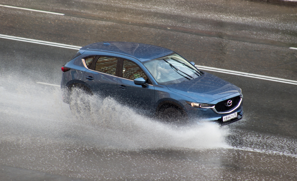 Mazda CX-5 splashing through standing water, i-ACTIV AWD traction, Mazda AWD service Daytona Beach FL, hydroplaning prevention, rainy season maintenance for CX-5 CX-50 CX-90, AWD differential fluid change, transfer case inspection, sensor connection check, matched tires and pressure, Daytona Mazda Service certified technicians