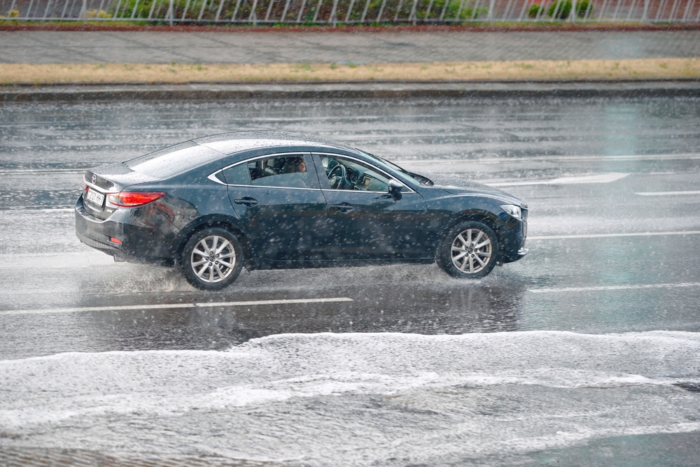 Mazda sedan driving in heavy rain, wet road spray, i-ACTIV AWD performance and stability, Daytona Mazda Service AWD maintenance, Daytona Beach Florida storms, AWD malfunction light diagnostic, tire tread and alignment check, brake service in wet conditions, safe highway merging and acceleration on slick pavement