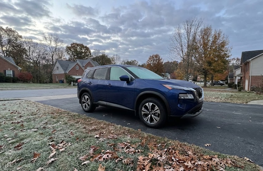 blue Nissan SUV parked in frosty Charlotte driveway at sunrise, cold weather fall and winter morning in North Carolina, light frost on grass and leaves, neighborhood near East Charlotte Nissan Service, example of cold temperatures causing TPMS warning light, Nissan Rogue ready for winter driving, Charlotte NC suburban street with parked Nissan, seasonal tire pressure changes in November and December, winter car care near East Independence Blvd