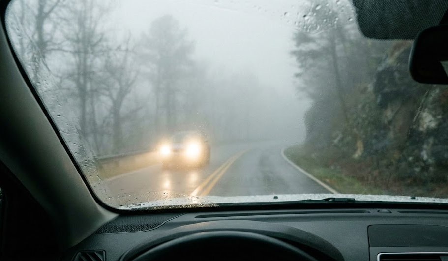 foggy East Tennessee mountain road, low visibility driving in Smoky Mountain fog, wet two-lane highway near Knoxville TN, Nissan driver struggling to see with cloudy headlights and worn wiper blades, dangerous night and rain conditions, visibility problems for Knoxville commuters, need professional headlight restoration and wiper replacement at Ted Russell Nissan Service Center, fog safety tips for I-40 and I-75 near the Smokies