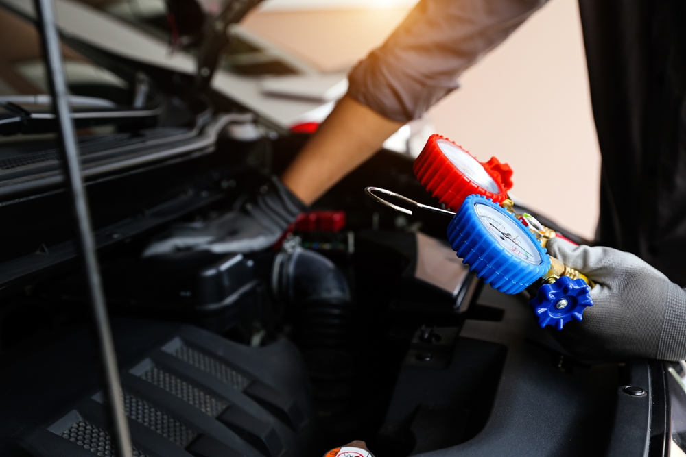 Ford technician using A/C diagnostic tools, certified A/C repair Murfreesboro TN, auto technician refrigerant gauge, Ford service center cooling system repair, expert compressor testing Ford trucks, summer A/C inspection Murfreesboro Ford service, Ford OEM tools for AC diagnosis