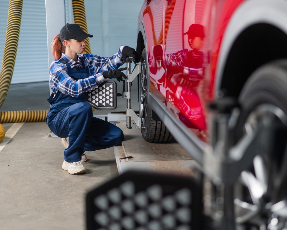 Ford of Franklin female technician performing wheel alignment, Ford alignment service Franklin TN, red Ford SUV on alignment rack, professional mechanic adjusting wheels, Ford certified service center near Nashville, precision alignment check Ford vehicle, Franklin TN Ford service department, tire balancing and alignment Ford service