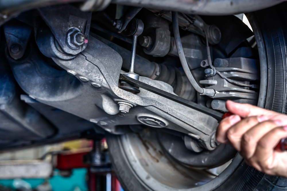 Close-up truck suspension repair, control arm and bushings, sway bar link inspection, wheel hub and alignment components, signs of wear clunking uneven tire wear nose-diving, Ford F-150 and Super Duty suspension service Murfreesboro TN, certified technician using tools, preventive maintenance for towing