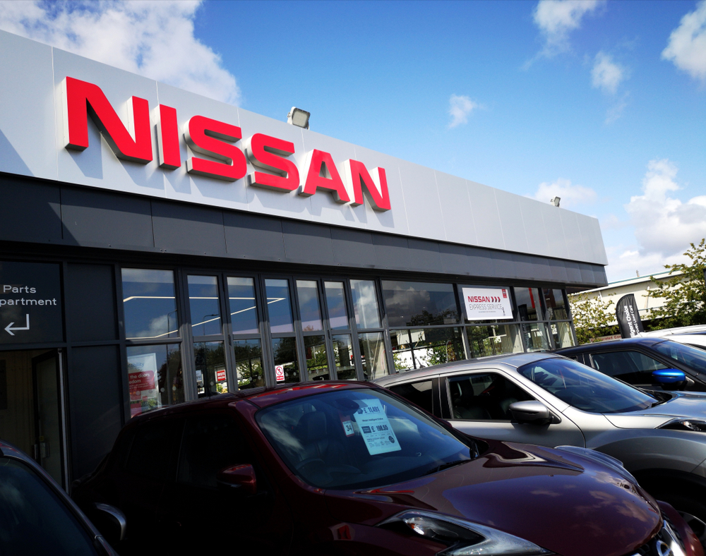 Exterior view of Gainesville Nissan Service Center with parked cars and service bays, convenient location for Nissan maintenance in Gainesville, FL