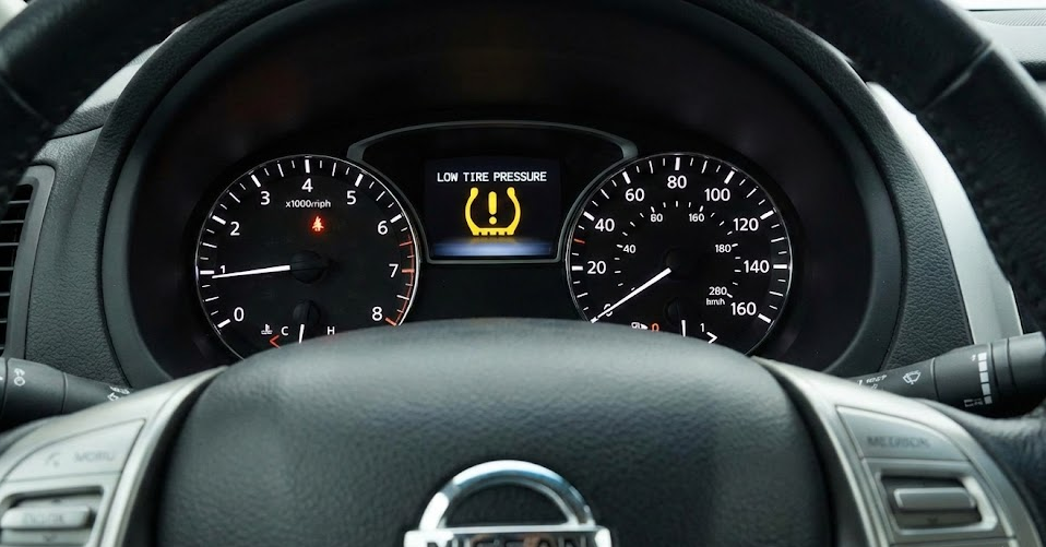 Nissan dashboard with low tire pressure TPMS warning light on, tire pressure monitoring system Gainesville FL, cold weather false flat tire alert, Nissan Easy-Fill Tire Alert education, why tire pressure light comes on in Gainesville winter, schedule TPMS diagnostic at Gainesville Nissan Service Center, safe Nissan driving with correct tire pressure