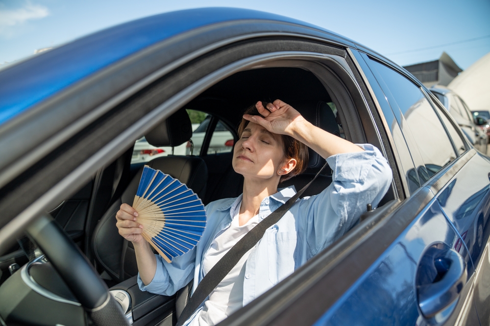 driver sweating in hot car, broken A/C in Ford, Florida summer heat, Palm Bay air conditioning repair, Ford A/C not cooling, driver fanning herself in Ford vehicle, car air conditioning problems Palm Bay
