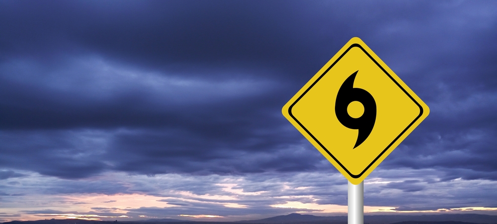 A hurricane warning sign under a stormy sky signals the need for Nissan storm prep and vehicle service at Naples Nissan Service Center in Naples, FL.