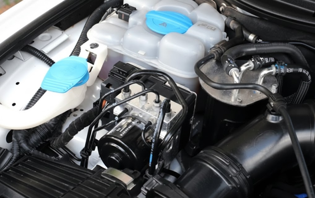 close up of modern engine bay, coolant reservoir and heater core hoses, INFINITI climate control components under hood, technicians inspect coolant level and heater core for defroster performance, Lake Norman INFINITI Service Center engine cooling system check, winter readiness inspection Cornelius NC, factory trained INFINITI technicians protecting defroster, heater core leak prevention, coolant flush and climate control maintenance near Davidson and Huntersville