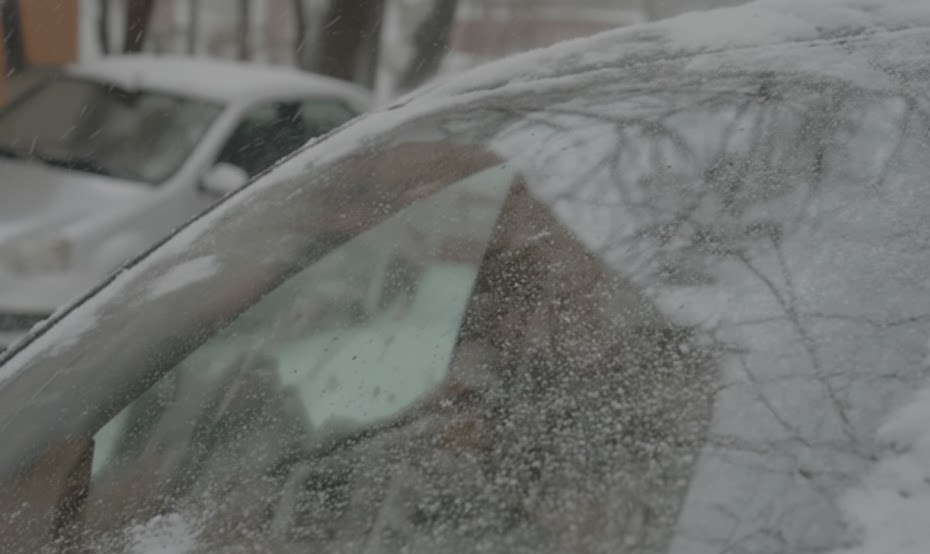frosted car windshield in winter storm, driver struggling to see through ice and snow, poor visibility on Lake Norman roads, unsafe winter driving conditions near Cornelius Davidson Huntersville NC, INFINITI sedan parked outside overnight, windshield completely covered with frost and freezing rain, reminder to service INFINITI defroster and climate control system at Lake Norman INFINITI Service Center, pre winter defroster inspection, visibility safety for I-77 commute and trips to Charlotte