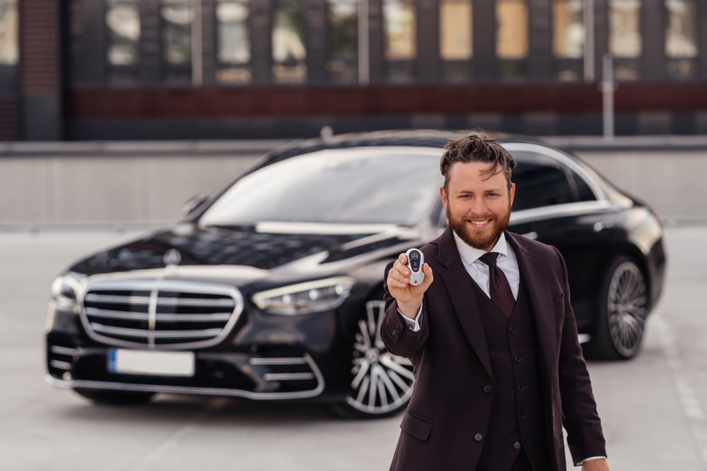 Mercedes-Benz owner holding key fob in front of S-Class, Mercedes digital key setup Daytona Beach FL, Mercedes key fob replacement cost, Mercedes-Benz dealer key programming, secure luxury vehicle access, Daytona Beach Mercedes key fob expert, Mercedes-Benz of Daytona Beach key solutions