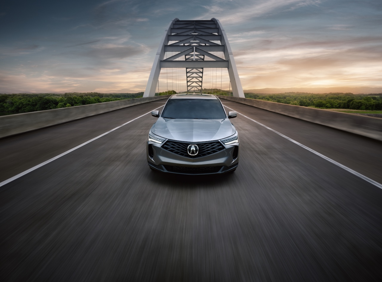 Luxury Acura RDX compact SUV driving on highway bridge at sunset, showcasing sleek design and premium appeal for drivers near Melbourne, FL
