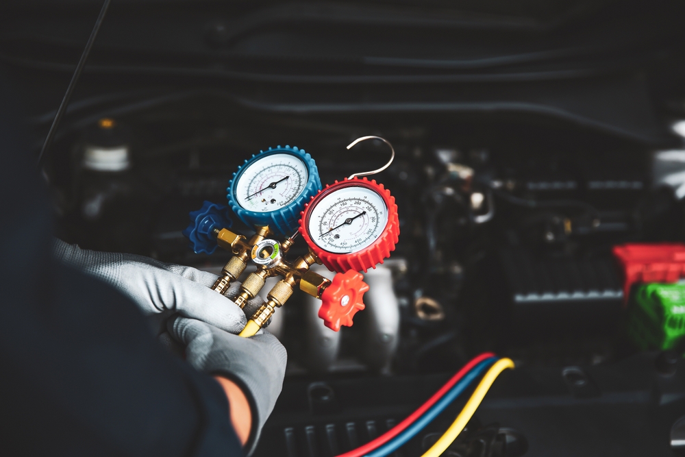 Nissan AC system diagnostic McDonough GA, auto technician checking AC gauges, refrigerant pressure test Nissan, professional AC service Henry County, car AC inspection tools, Nissan service center AC maintenance Georgia, air conditioning repair Nissan technician