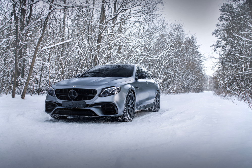 Mercedes-Benz 4MATIC sedan on snowy forest road, Mercedes-Benz of Westminster winter service, AWD stability in Colorado, Denver Front Range winter driving, proactive power distribution 4MATIC, luxury car snow performance, Colorado black ice conditions, Westminster CO Mercedes maintenance