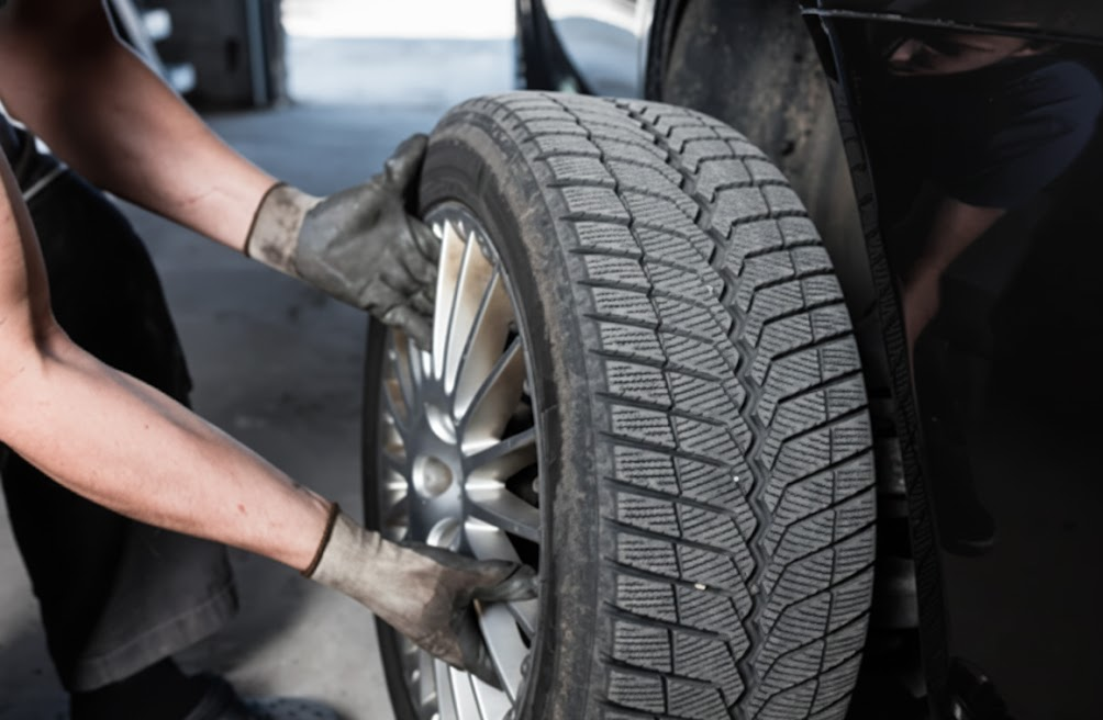 auto technician installing winter tire on alloy wheel, professional tire swap at Mercedes-Benz of Massapequa Service Center, seasonal tire change in Amityville NY, certified mechanics handling Mercedes-Benz AMG and C Class models, winter tire mounting and balancing, Long Island alignment check with tire service, Nassau County luxury vehicle maintenance, factory recommended tires for 4MATIC all wheel drive, cold weather preparation and safety inspection