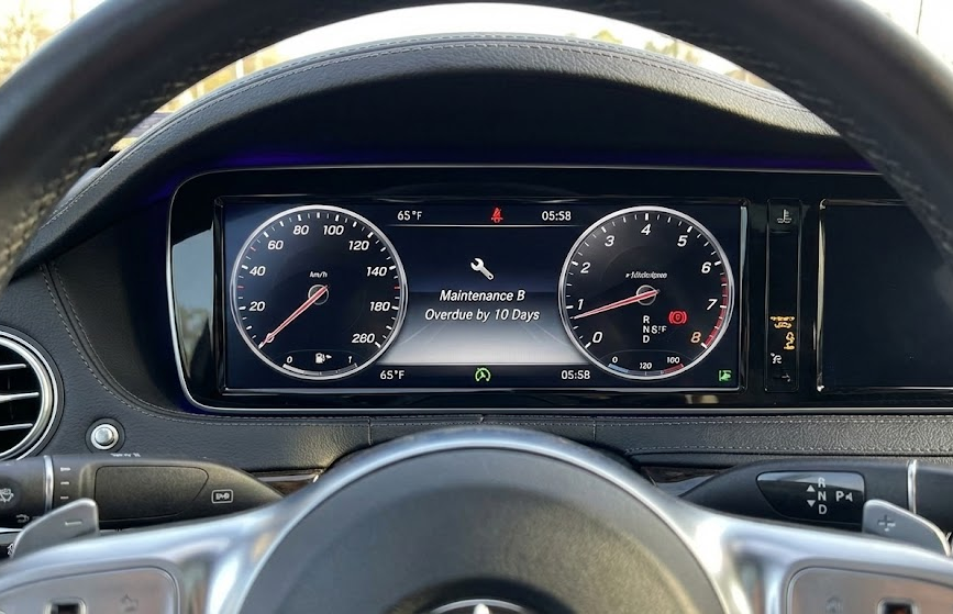 Mercedes-Benz digital instrument cluster showing Maintenance B overdue by 10 days, Service B reminder for Mercedes-Benz owners, dashboard warning before I-95 holiday travel, Mercedes-Benz of Daytona Beach pre-trip service, luxury car maintenance alert, Service A and Service B scheduler near Daytona Beach FL, Mercedes maintenance message interior view