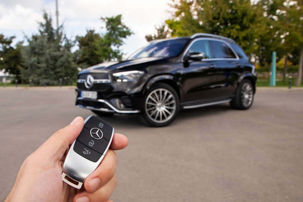 Mercedes-Benz key fob close-up with SUV in background, Keyless-GO not working in cold weather, key fob battery CR2032 replacement, emergency unlock Westminster CO, Mercedes-Benz of Westminster Service, Denver and Broomfield area Mercedes service, Keyless-GO troubleshooting guide, Colorado Front Range winter car tips, Mercedes door won’t unlock, schedule service Westminster Colorado