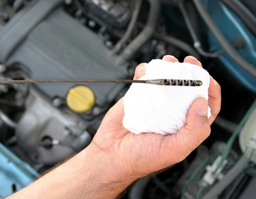 mechanic checking engine oil dipstick, Naples Nissan oil change service, Nissan Express Service oil and filter change Naples FL, fluid health inspection for stored vehicle, Gulf Coast snowbird car maintenance, degraded oil and moisture damage prevention, Nissan Rogue Altima Pathfinder oil level check, Naples Florida high heat engine protection, genuine Nissan oil and filter service near Vanderbilt Beach, post-storage oil change Naples Nissan Service Center