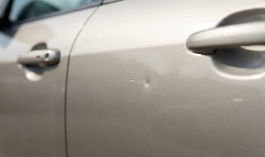 close up of small door ding and paint scratch on car door, minor cosmetic damage before lease return, Naples Premium Collision Center pre-lease repair, fix door dings and scratches Naples FL, luxury lease excess wear and tear example, body panel dent inspection, affordable collision repair Naples Florida