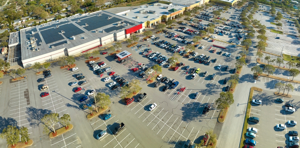 Naples FL mall parking lot sun exposure, vehicle UV risk outdoor parking, car paint damage from heat Naples, shopping center vehicle protection, Florida vehicle sun damage risk aerial view, protecting cars from UV rays in Southwest Florida, uncovered car parking Naples Florida