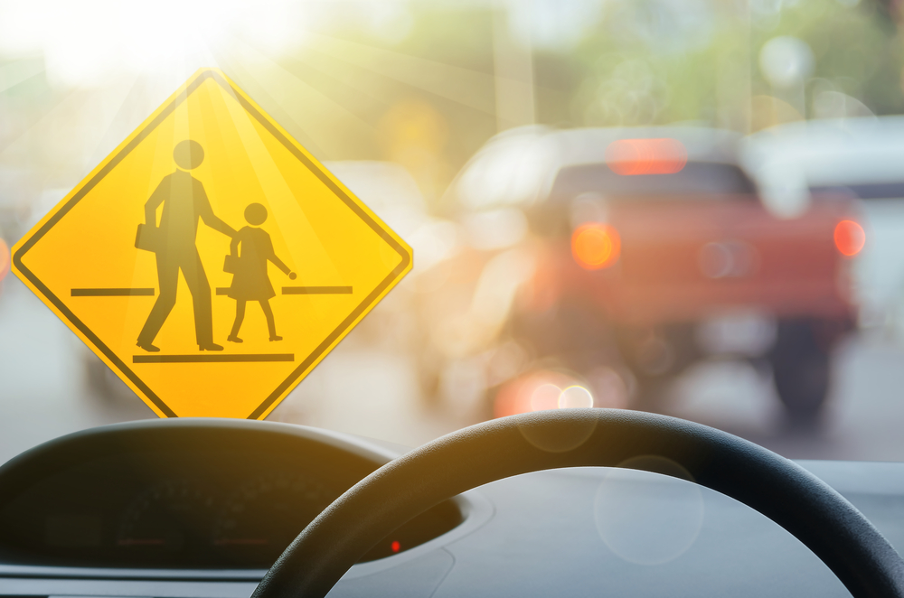 View from inside a Nissan highlighting a school zone crossing sign, emphasizing the need for reliable back-to-school brake service from Nissan of Cookeville for safety.