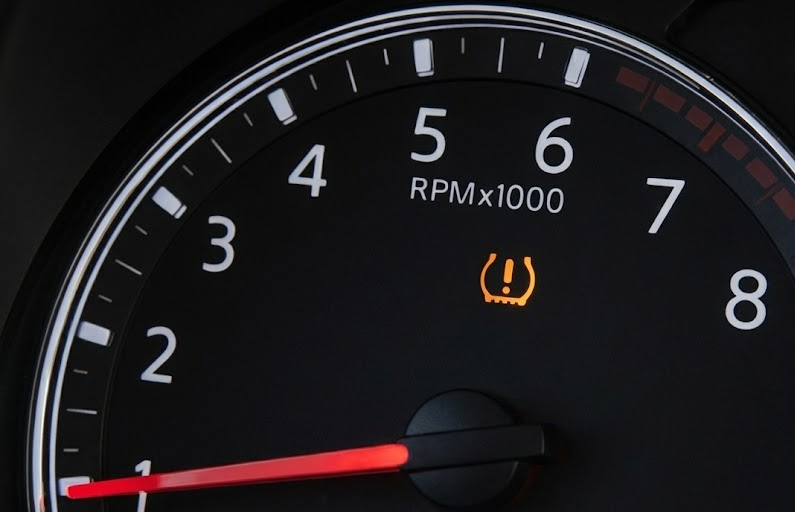 close up of Nissan TPMS warning light, tire pressure horseshoe symbol with exclamation point, dashboard gauge cluster in modern Nissan vehicle, tire pressure monitoring system alert, Knoxville TN cold weather tire pressure drop, Nissan safety technology, dashboard warning lights explanation, Ted Russell Nissan Service Center education, low tire PSI warning indicator, Nissan Rogue Altima Pathfinder Murano TPMS system, East Tennessee fall and winter driving safety