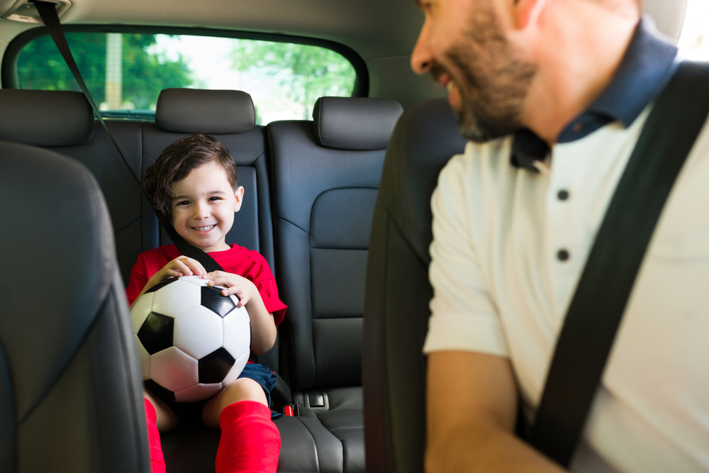 A father smiles at his son in a reliable Nissan SUV after a back-to-school service appointment, ready for safe drives to school and sports in Cookeville, TN.