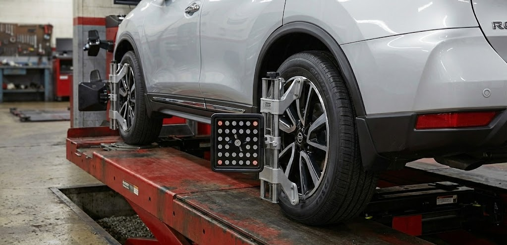 Nissan Rogue on computerized alignment rack, wheel alignment service Athens GA, factory-trained technician using alignment equipment, Nissan of Athens Service Center alignment check, protect Rogue and Altima tires, precise camber caster toe adjustment, pre-holiday alignment inspection, Nissan Safety Shield 360 sensor calibration, dealership alignment near UGA campus and Highway 316