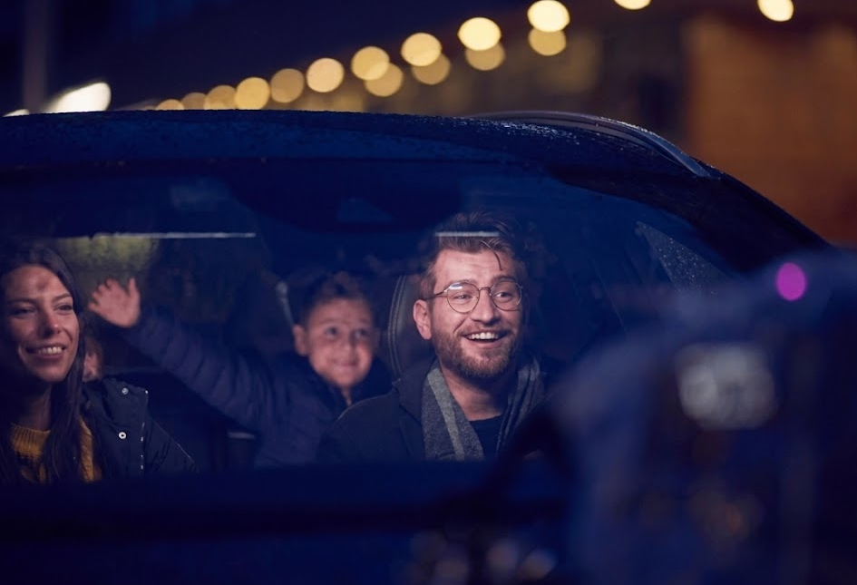 happy family riding together in car at night, smiling parents and child in front seats, confident nighttime driving with bright clear headlights, safe Nissan family road trip after headlight restoration, relaxed driver enjoying evening commute Cookeville TN, Nissan interior with cheerful passengers, Upper Cumberland family driving safety, Nissan of Cookeville service customer satisfaction, peace of mind after professional headlight aiming and restoration