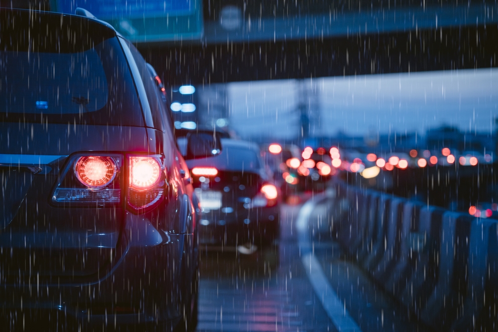 Nissan taillights glow in heavy rain during hurricane evacuation traffic in Florida, highlighting the critical need for reliable brakes and tires from Naples Nissan Service Center.