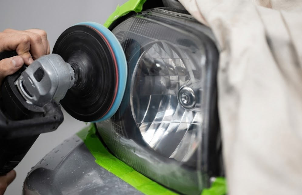 Professional headlight restoration process on Nissan vehicle, technician polishing oxidized headlight lens with rotary buffer, restoring cloudy headlights to factory clarity, UV damage removal on polycarbonate headlamp, Colorado Springs high-altitude sun causing headlight oxidation, dealership-grade headlight restoration service, improved nighttime visibility and safety, Nissan service center in Colorado Springs, South Colorado Springs Nissan professional automotive detailing and safety maintenance