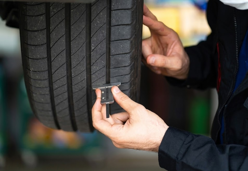 Technician measuring tire tread depth with gauge, 3/16 inch requirement Colorado Traction Law, Code 15 tire inspection at South Colorado Springs Nissan, service advisor checking winter tire wear, Nissan service center Colorado Springs Academy Blvd, safe tread depth for snow and ice, Code 15 compliant winter tires, professional tire check before Monument Hill drive, Nissan Rogue Pathfinder Altima tire service, Colorado winter driving preparation