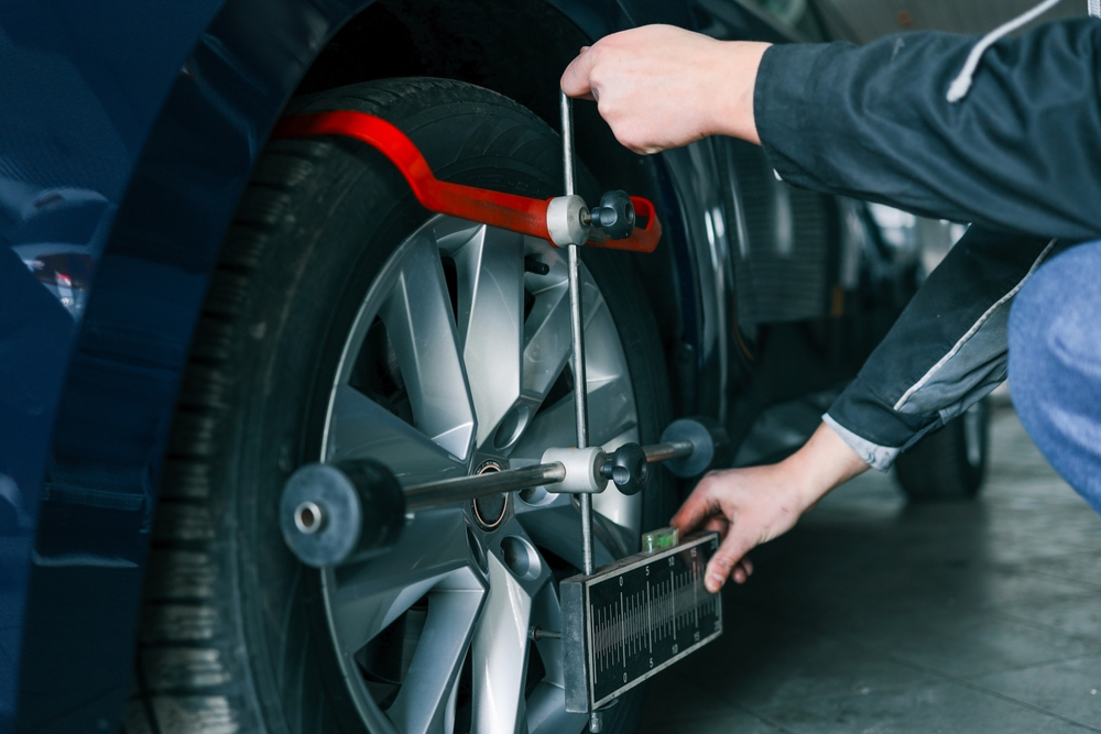 Certified Nissan technician performing wheel alignment, professional wheel alignment equipment, South Colorado Springs Nissan alignment rack, OEM alignment specs, precise suspension adjustment, Nissan service center Colorado Springs, alignment check service