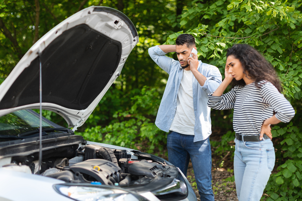 Stranded couple with dead battery in summer, overheating car battery Athens GA, emergency roadside assistance for Nissan drivers, Nissan battery failure warning signs, heat-damaged car battery Athens Georgia, dead battery repair Nissan of Athens dealership