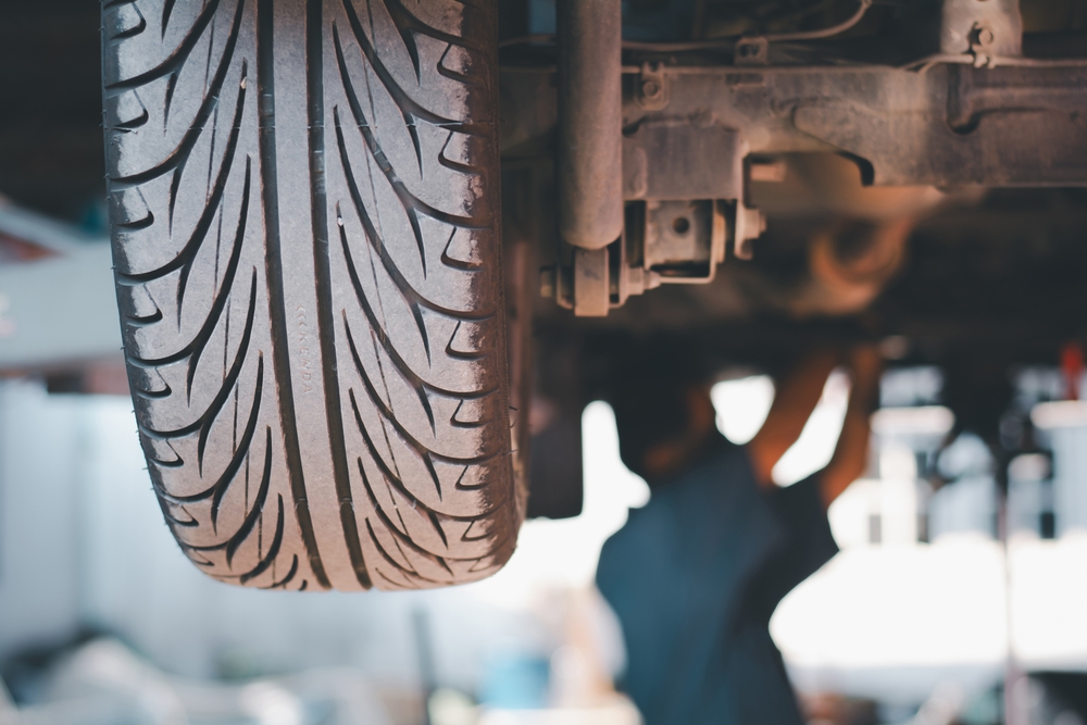 Toyota tire inspection Knoxville TN, undercar tire view, summer tire service, technician examining tires, Knoxville Toyota tire safety check, wheel alignment service, Toyota tire tread depth check Knoxville