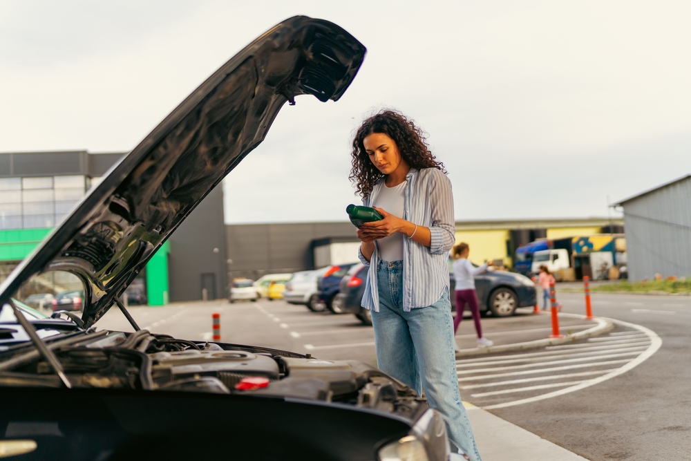 UGA student checking engine oil in Athens GA, car trouble in campus parking lot, female college student with hood open, Athens Collision Center emergency diagnostics, student vehicle maintenance before class