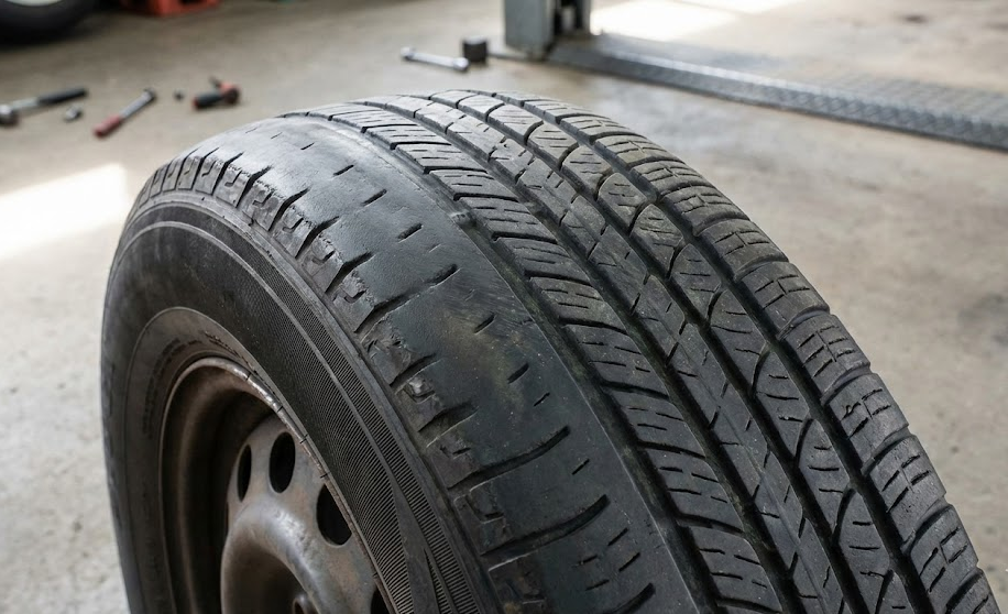Close up of uneven tire wear caused by bad wheel alignment, worn inner edge of tire tread, Nissan tire safety inspection McDonough GA, Henry County Georgia fall driving tires, alignment problems destroying tires, need for Nissan tire rotation and replacement, McDonough Nissan tire center, tread wear pattern from misaligned wheels, improve fuel economy and safety with alignment, Nissan service coupons for tire and alignment checks