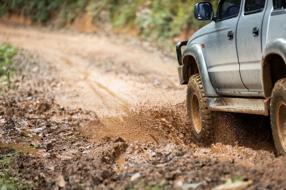 Nissan SUV navigating muddy Colorado mountain road, rough terrain brake wear, off-road conditions near Colorado Springs, dirt road elevation challenges, mountain road impact on brake performance, Pikes Peak road conditions, Colorado Nissan brake service